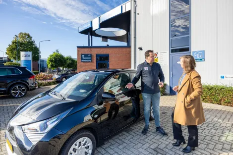 Vrouw en autoverkoper naast auto